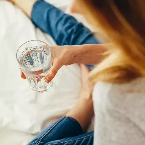 Žena drži čašu vode zbog mamurluka