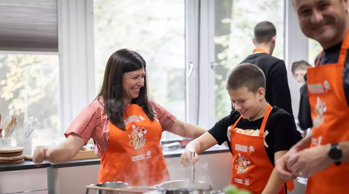 Žena, dječak i muškarac se smiju i pripremaju zdravi obrok u sklopu inicijative Inkubator Motivator